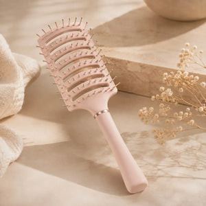 Pale pink anti-static vent brush displayed on a soft neutral background for gentle detangling and faster blow-drying.