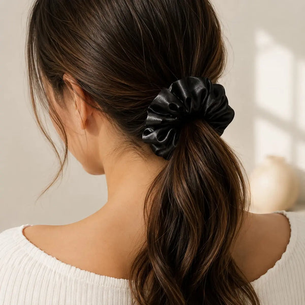 Woman wearing a black 30 momme 6A silk scrunchie in a loose low ponytail