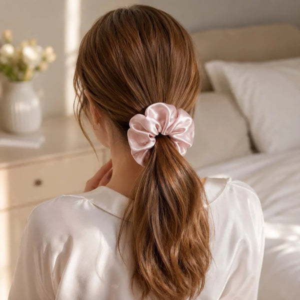 Woman wearing a pink 30 momme 6A silk scrunchie in a loose low ponytail