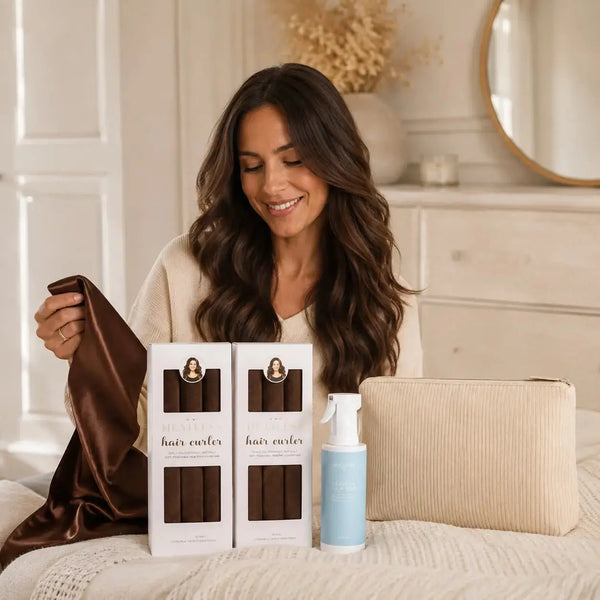 Woman holding a brown satin scarf beside Revitalysse brown heatless curlers, hair mist and corduroy pouch