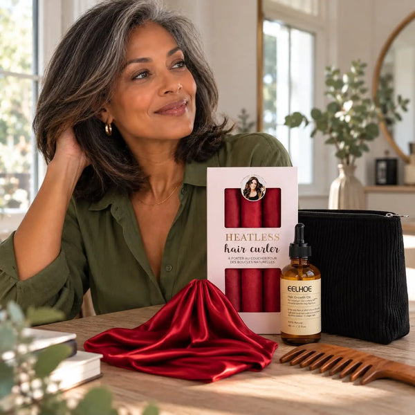 Mature woman with shoulder-length salt-and-pepper wavy hair showcasing red heatless curlers, hair serum, black cosmetic pouch, red satin bonnet and wooden wide-tooth comb.