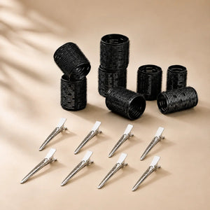 Black volume hair rollers with metal clips arranged on a neutral background for creating root lift and blowout-style volume.