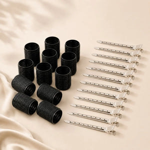 Black volume hair rollers with silver metal clips arranged on a neutral background for creating root lift and blowout-style volume.