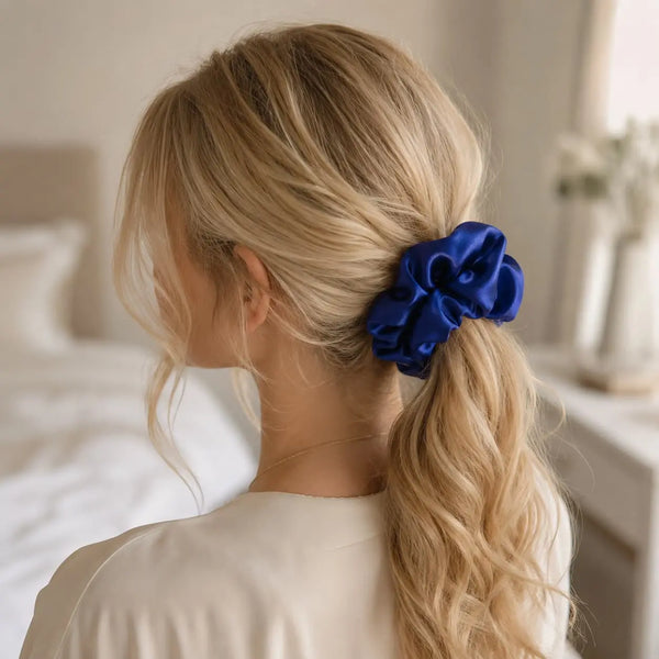 Blonde woman wearing a royal blue 30 momme 6A silk scrunchie in a loose low ponytail