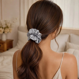 Woman wearing a silver 30 momme 6A silk scrunchie in a loose low ponytail